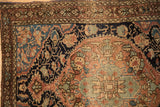 Corner detail of an antique Sarouk rug showing a starburst border and textured, low pile.