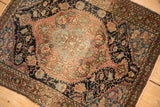 Traditional antique Sarouk rug with a floral medallion, showing its low pile and rich patina.