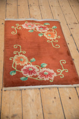 Vintage Art Deco rug mat from an angle showing the reciprocal floral bouquets on a copper field.