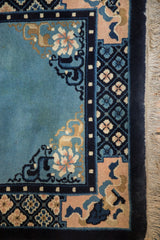 Detail of a vintage Chinese rug corner with pale rose floral motifs and a cobalt blue pearl-design border.