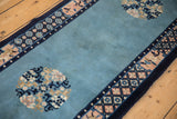 Patina on the sky blue field of a vintage Peking runner, showing a floral roundel and detailed cobalt border.