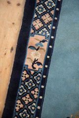 Close view of a vintage Peking rug's border with pearl details and pale rose floral vines.