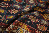Close view of the dense, tribal boteh motifs and low pile on this antique Caucasian rug.