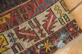 Detail of the worn, tattered corner of an antique rug showing adhesive residue.