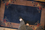 Vintage Art Deco rug with a cobalt blue field and corner floral sprays, viewed for scale.