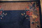 Corner of a vintage Art Deco rug showing floral sprays, a brown border, and visible white knot heads.