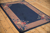 Perspective view of a vintage Art Deco rug's open blue field and floral-adorned corners.