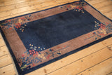 Angled view of a vintage Art Deco rug showing the cobalt blue field and floral border design.