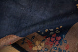 A folded corner of a vintage Art Deco rug, revealing its hand-knotted back and floral pattern.