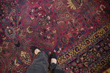 Close-up of the delicately executed floral vines on the aubergine purple field of a vintage Persian carpet.