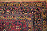 Delicately executed floral borders in saffron, navy, and aubergine on a vintage Meshed carpet corner.
