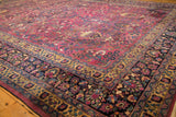 The vintage Meshed carpet's corner with its navy floral main border and saffron guard bands.