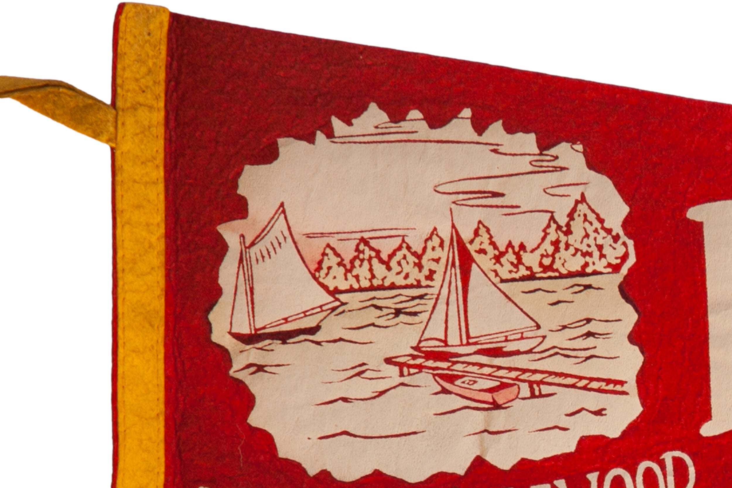 Close-up of the vintage pennant's red felt texture and off-white sailboat illustration.