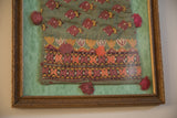 Ornate gold frame and dark pink silk pom-pom on the antique textile pouch.