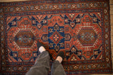 Person's view of a vintage Karaja rug's triple medallion design, showing scale.