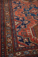 Angled view of the vintage Karaja rug's lightning blossom and starburst floral border.