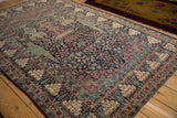 Angled view of an antique Tehran rug's refined floral field and complex pomegranate borders.