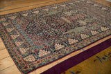 Angled view of a Tehran rug's dense floral field and symbolic pomegranate borders.