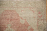Detail of the worn, hand-knotted pile on a distressed Oushak in pale seafoam and dusty red.