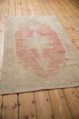 A long perspective view of the vintage Oushak's abrashed field and dusty ruby red medallion.