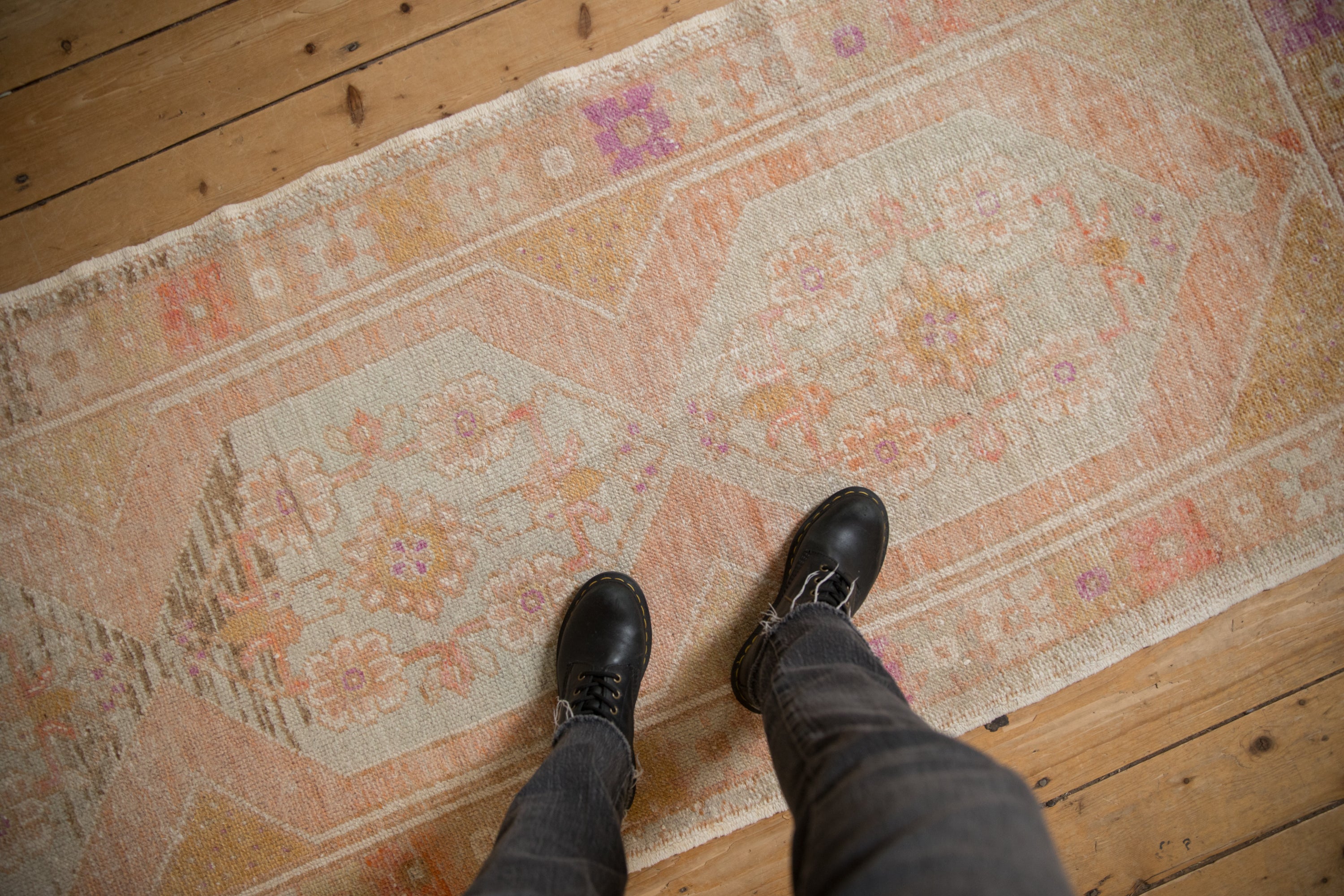 Time-softened texture of a distressed Oushak runner in pale tangerine, gold, and aubergine hues.