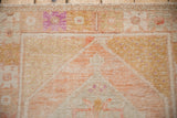 Close-up of a vintage Oushak's distressed pile, showing geometric florals in tangerine and aubergine.