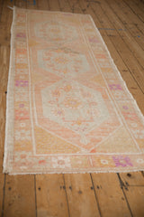 Vintage Oushak runner from an angle, displaying repeating hexagonal medallions and time-softened colors.