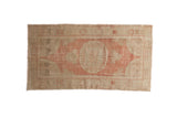 Vintage distressed Oushak rug runner with a roundel medallion in muted dusty blush and sand tones.