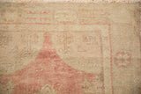 Even wear on the hand-knotted pile of a distressed Oushak rug in sand and dusty blush.