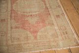 Corner view showing the evenly worn pile and faded pomegranate border of the Oushak rug.