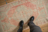 Low-pile texture of a distressed Oushak runner in faded ruby red and pale seafoam green.