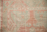 Corner spandrel detail with checkered designs in pale ruby red and seafoam on a worn, low pile.