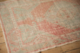 Angled corner view of a distressed Oushak rug showing soft wear to the knot heads.