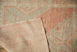 Corner detail of the distressed Oushak rug showing its hand-knotted foundation and low pile.