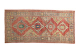 Distressed Oushak runner with a column of geometric diamond medallions in ruby red, green, and saffron yellow.