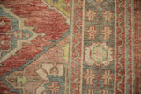 Close-up of a vintage Oushak rug's worn pile, showing ruby red, mallard green, and sapphire blue details.