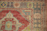 Geometric borders in mallard green, ruby red, and ivory on a distressed Turkish Oushak rug.