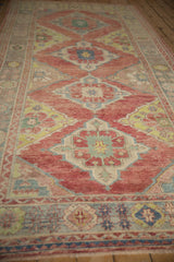 Low angle view down a distressed Oushak runner with repeating ruby red diamond medallions.