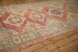 Lengthwise view of the distressed Oushak runner's ruby red and mallard green design.