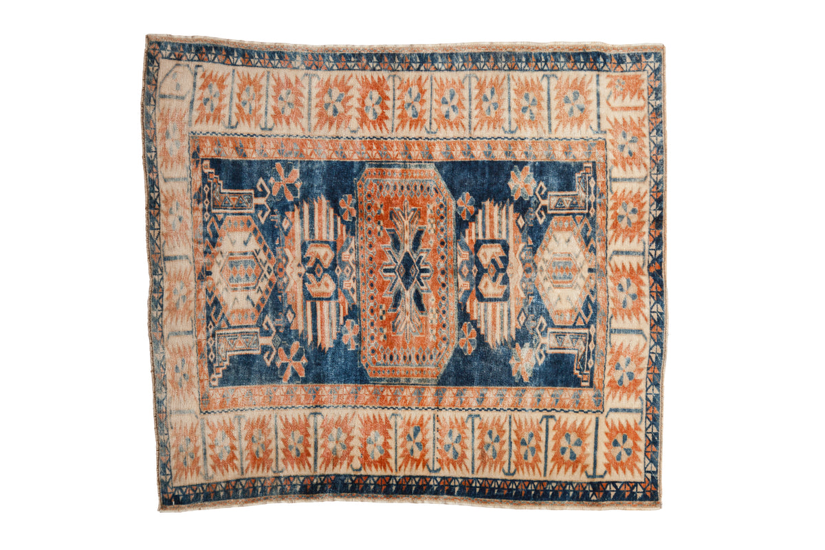 A distressed vintage Turkish Oushak rug with a central terracotta medallion on a saturated indigo blue field and a contrasting ivory border.