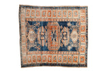 A distressed vintage Turkish Oushak rug with a central terracotta medallion on a saturated indigo blue field and a contrasting ivory border.