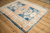Distressed vintage Oushak rug viewed at an angle, showing the geometric border and indigo blue field.