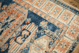 Angled close-up of the distressed Oushak rug's serrated palmette border in indigo and terracotta.