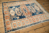 A distressed vintage Oushak rug's decorative pattern in indigo and terracotta, viewed from an angle.