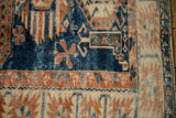 Close-up of a vintage Oushak rug's corner, showing the serrated palmette border and short indigo pile.