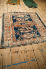 Angled perspective of a vintage distressed Oushak rug showing its indigo, terra cotta, and ivory design.