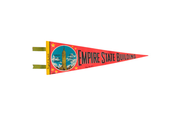 A vintage red felt Empire State Building pennant with a colorful graphic and yellow header.