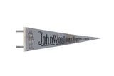 Vintage John Woodman Higgins Armory felt pennant with a knight graphic on a grey background.