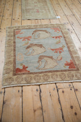 Corner of Modern Oushak rug, powder blue, cinnabar bell flowers, spiral border, and fringe.