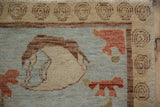 Modern Oushak rug close-up: unique spiral border, thin stripe, powder blue field with cinnabar flowers.
